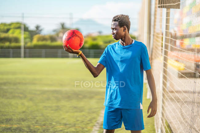 Nero adolescente in possesso di palla rossa sul campo di calcio — Foto stock