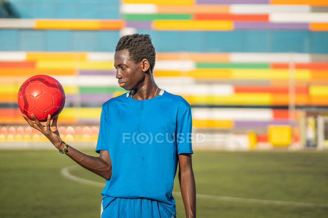 Schwarzer Teenager mit Fußballball gegen Stadionsitze — Stockfoto