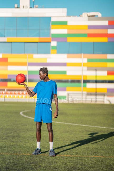 Черный подросток с футбольным мячом против мест на стадионе — стоковое фото