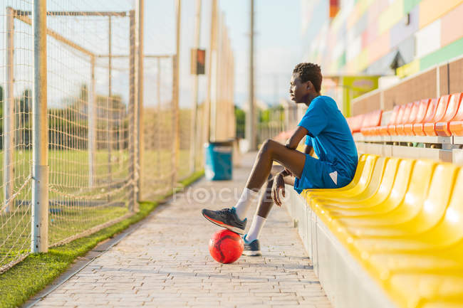 Вид сбоку на афроамериканского футболиста, отдыхающего на стадионе — стоковое фото
