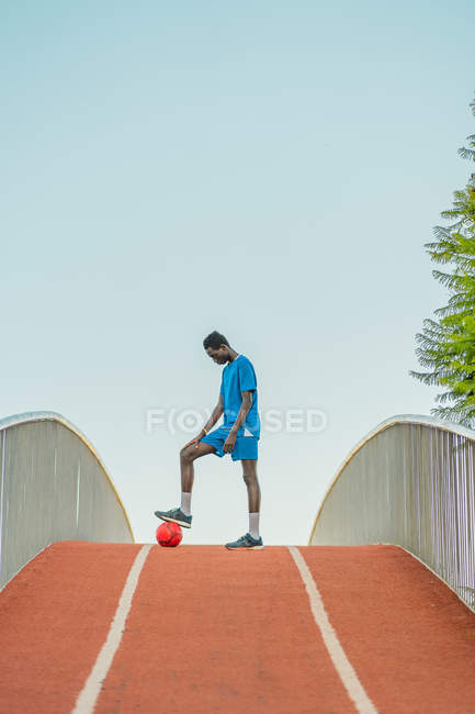 Ethnic football player standing on path of sport stadium — Stock Photo