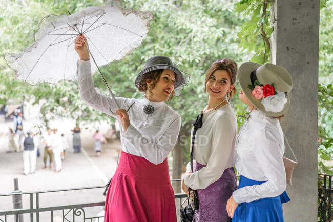 Vintage femminile apertura ombrellone vicino amici — Foto stock