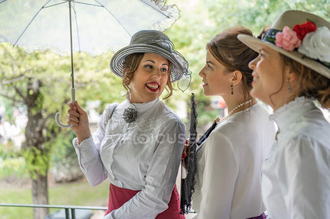 Vintage female opening parasol near friends — Stock Photo