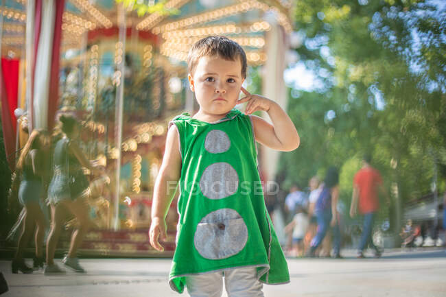 Niño de pie cerca de carrusel en movimiento y soñando en la feria - foto de stock