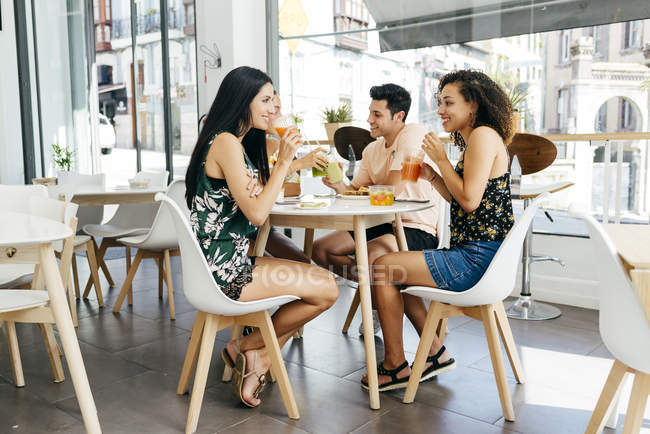 Divers amis au repos avec des smoothies assis dans un café — Photo de stock