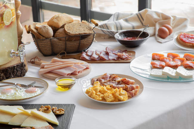 De cima vista do ambiente de mesa aconchegante composto por ovos fritos e bacon salmão queijo refeição e padaria em casa — Fotografia de Stock