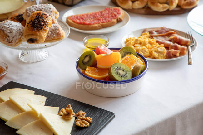 Desde arriba de las secciones de naranjas y pomelos y kiwi en el ambiente elegante de la mesa con lino blanco. - foto de stock