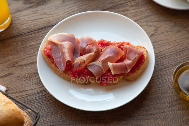 Зверху смачний іспанський тост з помідорами та беконом на сніданок на дерев'яному столі — стокове фото
