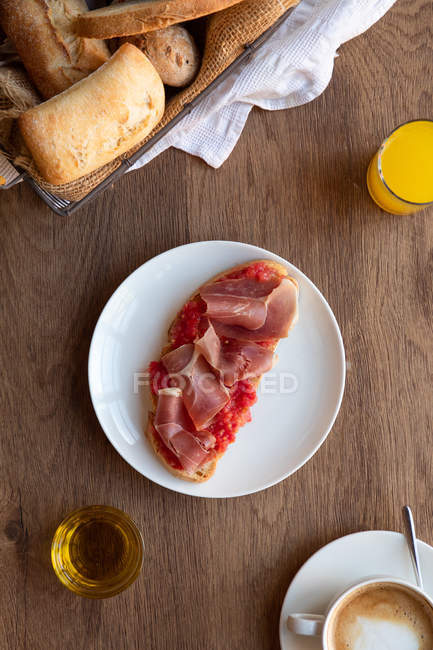 Dall'alto di pane tostato spagnolo saporito con pomodoro e pancetta per colazione su tavolo di legno — Foto stock