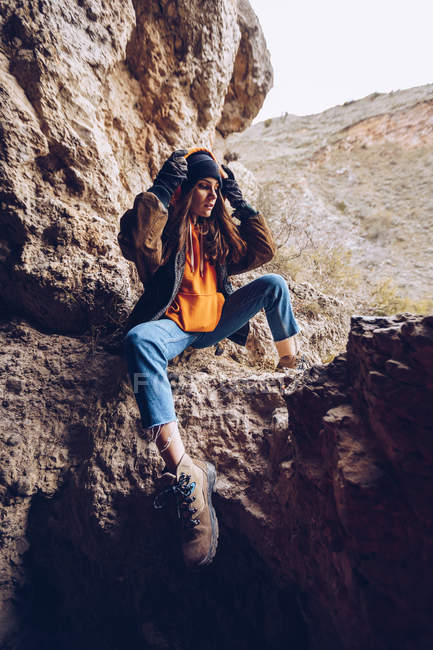 Calm woman in warm wear sitting on mountain cliff — Stock Photo