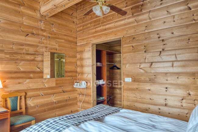 Intérieur confortable de la chambre d'hôtel de campagne avec mur en bois et lit confortable — Photo de stock