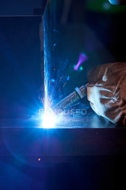 Cropped image of craftsman wearing gloves working in workshop and soldering metal construction — Stock Photo