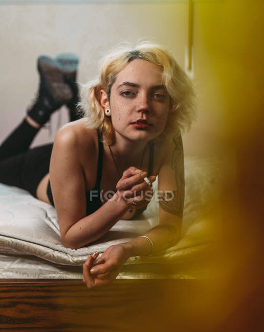 Mujer pecosa pensativa segura fumando en la cama - foto de stock