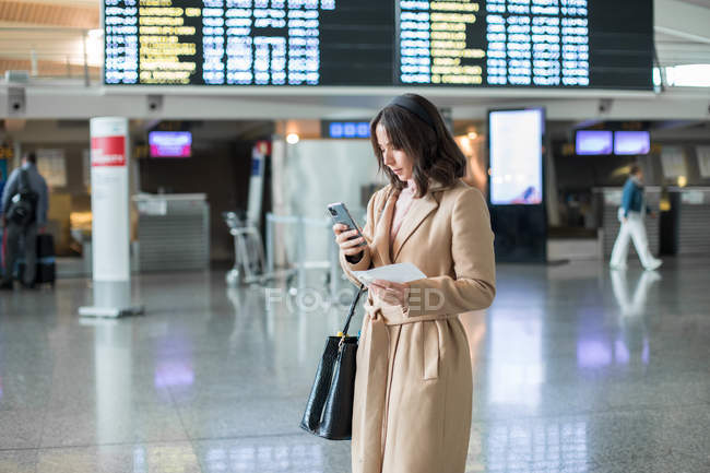 Frau nutzt Smartphone am Flughafen — Stockfoto