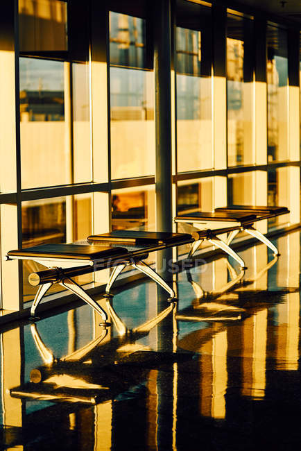 Metal bench with leather black seats along glass wall in sunny hallway of airport in Texas — Stock Photo