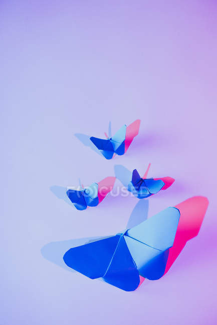 Рожеві і сині метелики прикріплені до бузкової стіни — стокове фото