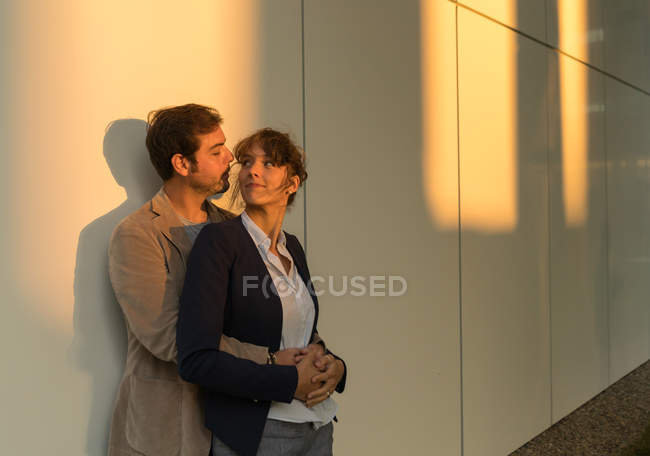 Geschäftsmann umarmt Freundin, während er nach Feierabend vor modernem Gebäude steht — Stockfoto