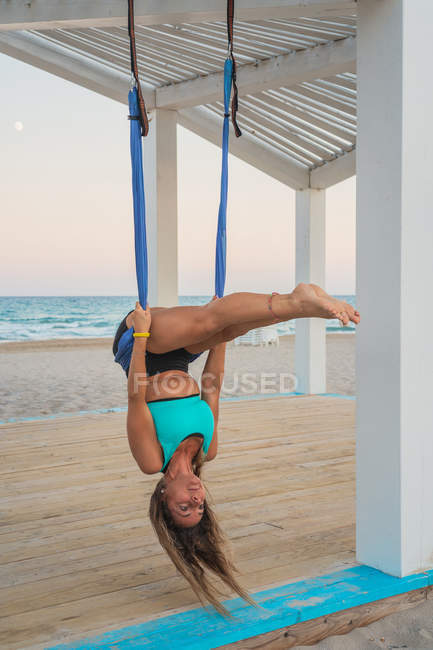 Donna rilassata che esegue yoga aereo appeso testa verso il basso — Foto stock