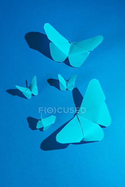 Fragile blue butterflies made of paper and attached to blue silk fabric — Stock Photo