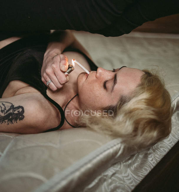 Selbstbewusste nachdenkliche sommersprossige Frau, die im Bett raucht — Stockfoto