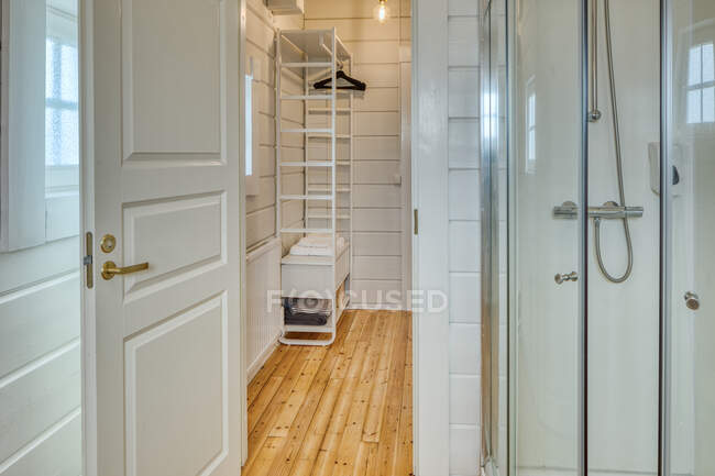 Elegante bagno minimalista interno con pavimento in legno e pareti bianche con piccola finestra a casa — Foto stock
