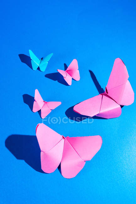 Zarte rosa Schmetterlinge aus Papier, die an blauem Seidenstoff befestigt sind — Stockfoto