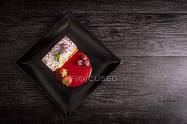 Diphlomate cream and red fruit strudel in elegant black plate — Stock Photo