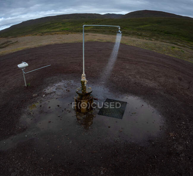 Sauberes Wasser fällt auf nassen Schmutz in der Nähe von Hügeln an bewölkten Tagen in der Natur in Island — Stockfoto