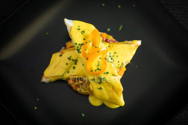 Corvina con salsa di peperoni gialli in piatto nero — Foto stock