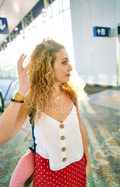 Curly woman with backpack walking in light airport hall in Texas — Stock Photo