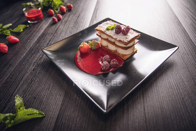 Crema de diflomato y strudel de fruta roja en elegante plato negro - foto de stock