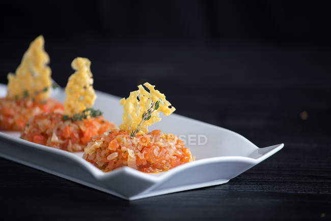 Fragrant appetizing Quenelles of tomato fondue and Parmensan tile in white figured plate on gray background — Stock Photo