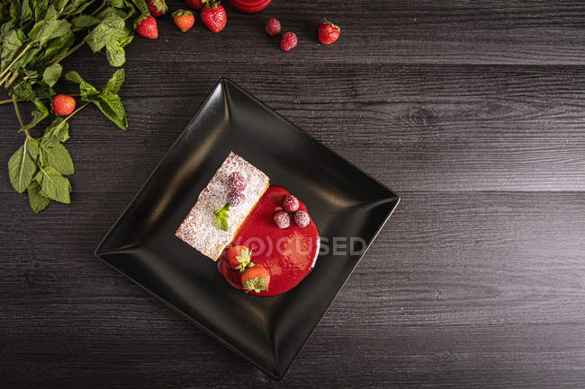 Diphlomatcreme und roter Fruchtstrudel in elegantem schwarzen Teller — Stockfoto