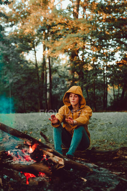 Donna in viaggio mani di riscaldamento vicino al falò sulla radura della foresta — Foto stock