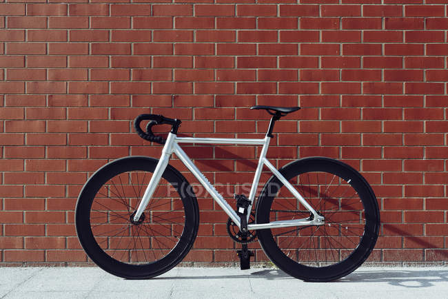 Новий сучасний велосипед з чорною ручкою, припаркований на стіні з червоної цегли — стокове фото