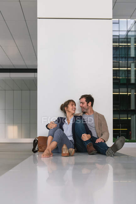 Чоловік менеджер обіймає і цілує дівчину, сидячи за межами офісної будівлі на міській вулиці після роботи — стокове фото