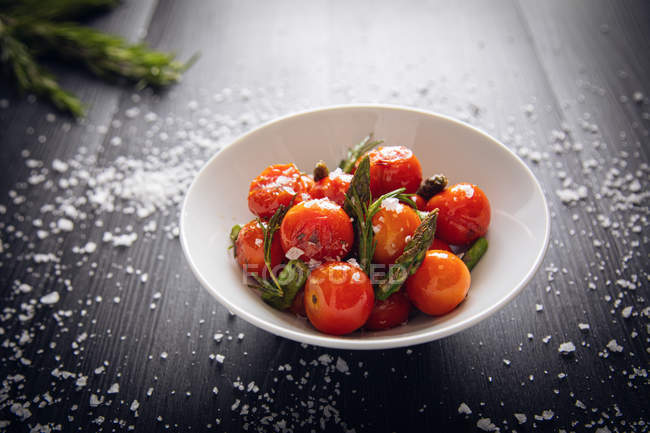 Tomates cherry frescos salteados con espárragos verdes y romero - foto de stock