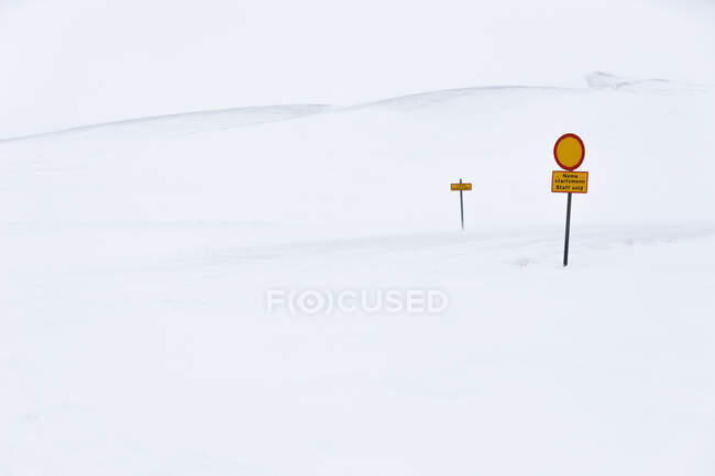Red and yellow caution signposts located in middle of snowy nature on cold winter day in Iceland — Stock Photo