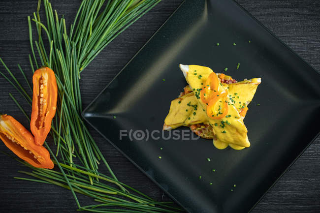 Corvina avec sauce au poivron jaune dans une assiette noire — Photo de stock