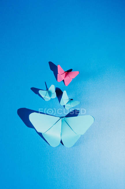 Borboletas frágeis feitas de papel e ligadas ao tecido de seda azul — Fotografia de Stock