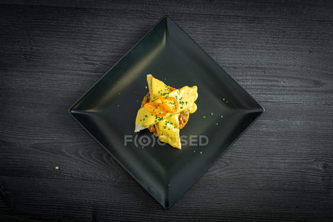 Corvina mit gelber Pfeffersauce in schwarzem Teller — Stockfoto