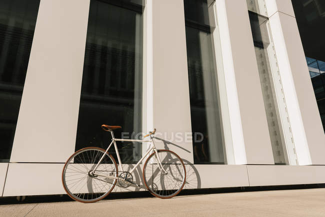 Bike parcheggiata sul marciapiede vicino al muro di edificio contemporaneo nella giornata di sole sulla strada della città — Foto stock