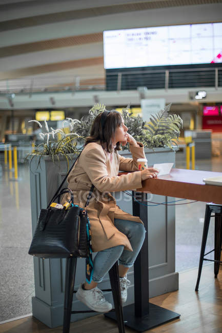 Donna seduta e utilizzando smartphone in aeroporto — Foto stock