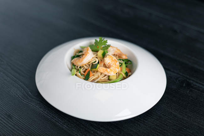 From above fragrant appetizing Pad Thai of vegetables and prawns in white plate on gris background. - foto de stock