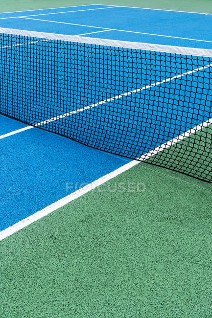 Detail of blue and green outdoor tennis court with black net. — Stock Photo