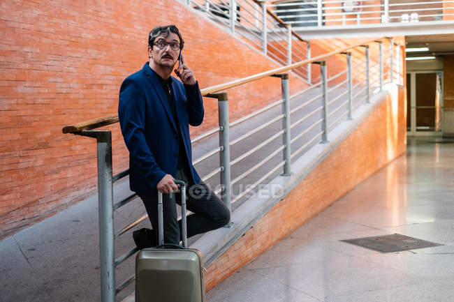 Homme âgé debout avec des bagages et parlant sur smartphone — Photo de stock