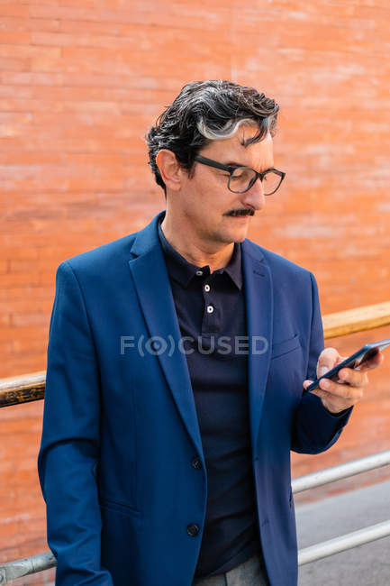 Reifer Geschäftsmann in blauer Jacke nutzt Smartphone — Stockfoto