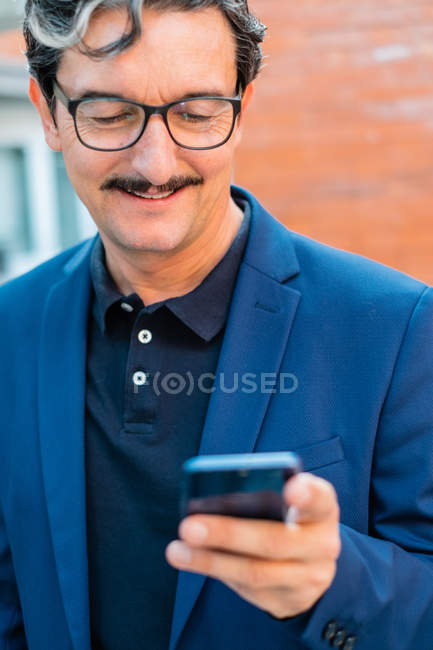 Uomo d'affari anziano in giacca blu con smartphone — Foto stock