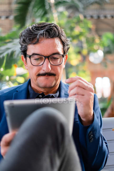 Старий вродливий чоловік на вулиці користується цифровим планшетом. — Stock Photo