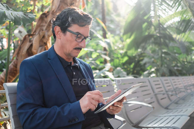 Hombre guapo envejecido usando tableta digital al aire libre - foto de stock